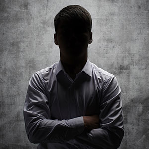 A man in a white shirt standing in front of a wall.